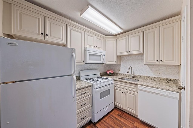 kitchen featuring a sink, light stone countertops, white appliances, and dark wood finished floors