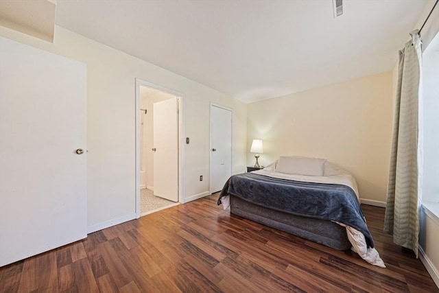 bedroom with baseboards, connected bathroom, wood finished floors, and visible vents