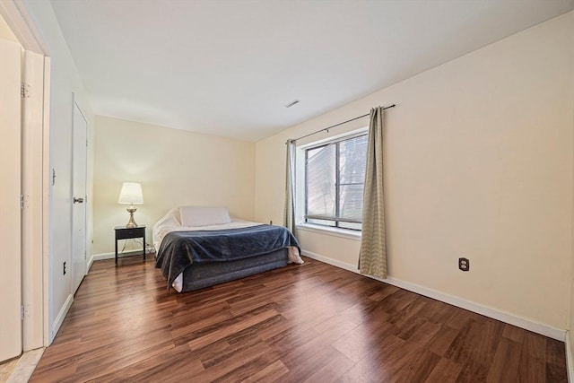 bedroom featuring baseboards, wood finished floors, and visible vents