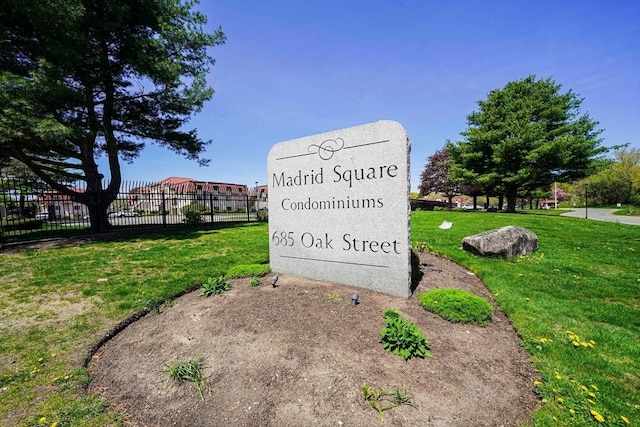 community / neighborhood sign featuring a lawn and fence