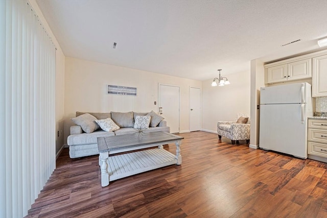 living room featuring baseboards, visible vents, wood finished floors, and a chandelier