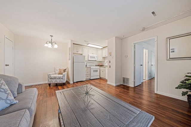 living room with a chandelier, baseboards, visible vents, and wood finished floors