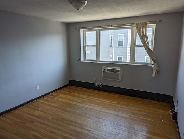 spare room featuring plenty of natural light, hardwood / wood-style floors, and an AC wall unit