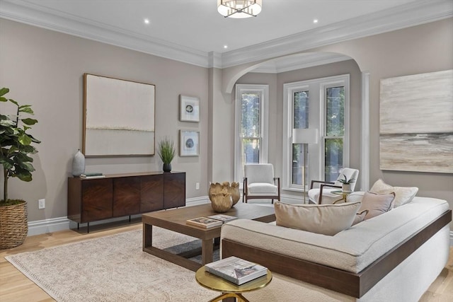 living area featuring baseboards, arched walkways, wood finished floors, and ornamental molding