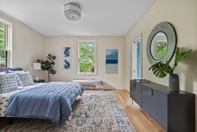 bedroom featuring multiple windows, light hardwood / wood-style flooring, and ornamental molding