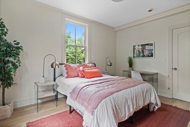 bedroom with crown molding and light hardwood / wood-style flooring