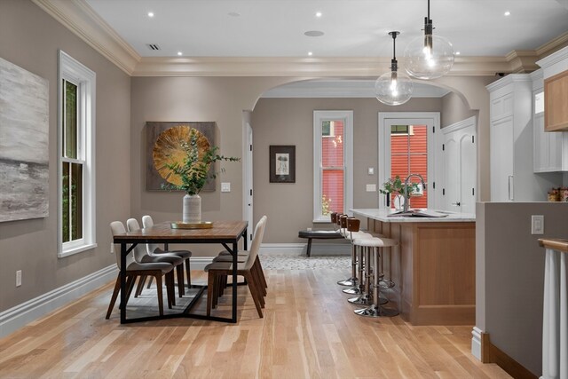 dining area with ornamental molding, a wealth of natural light, and light wood-type flooring