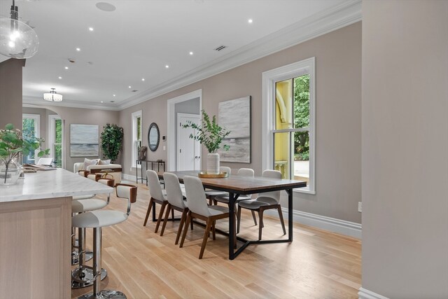 dining room with light hardwood / wood-style floors and crown molding