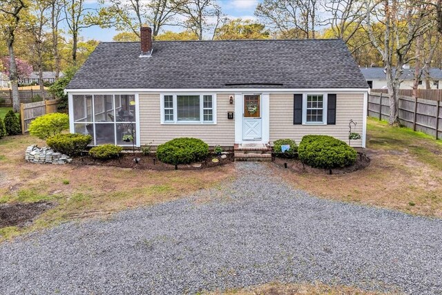 new england style home featuring fence, a shingled roof, a chimney, and a sunroom