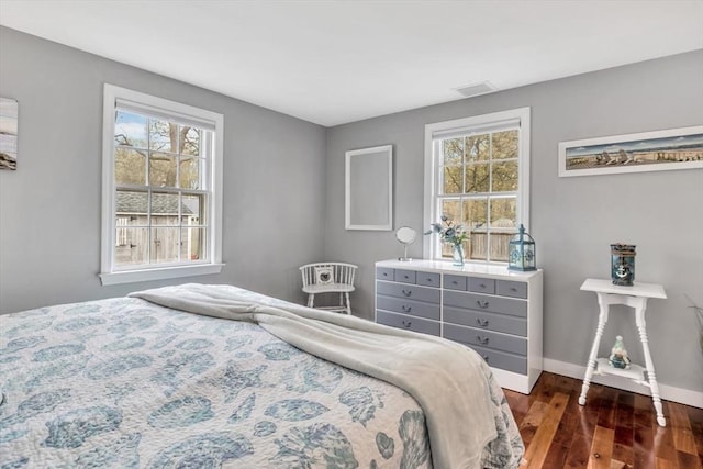 bedroom with dark wood-type flooring, multiple windows, and baseboards