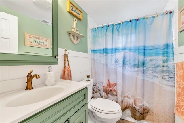 bathroom featuring vanity, toilet, a shower with curtain, and a wainscoted wall