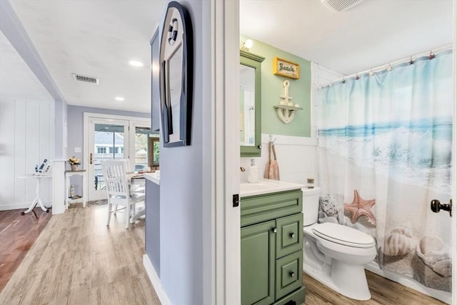 full bathroom with wood finished floors, toilet, vanity, a shower with curtain, and a wainscoted wall