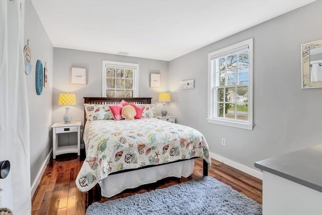 bedroom with multiple windows, baseboards, and wood finished floors