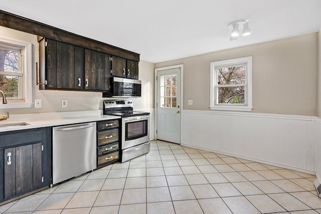 kitchen with a wealth of natural light, dark brown cabinets, light tile patterned floors, and stainless steel appliances