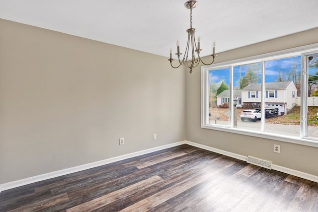 spare room with dark hardwood / wood-style flooring and a chandelier