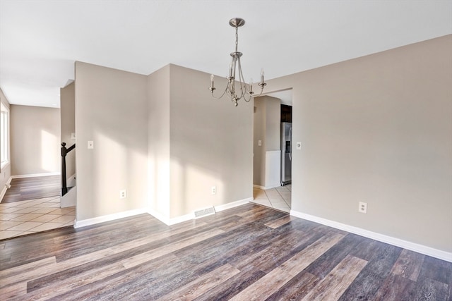 spare room featuring hardwood / wood-style flooring and a notable chandelier