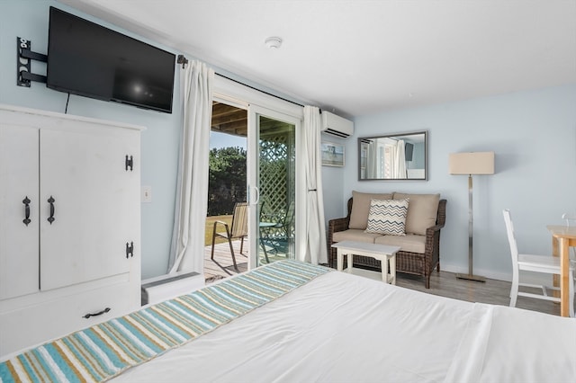 bedroom featuring a wall mounted air conditioner, access to outside, and light hardwood / wood-style flooring