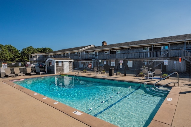 view of pool featuring a patio and a storage shed