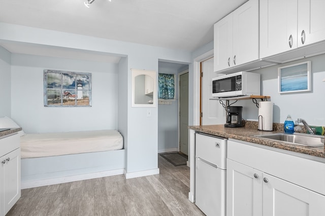 kitchen with white appliances, sink, white cabinets, and light hardwood / wood-style floors