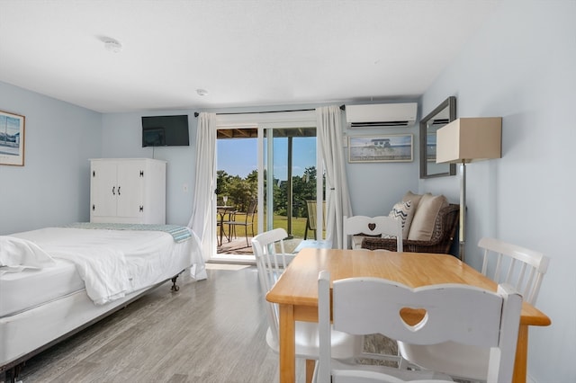 bedroom featuring an AC wall unit, light wood-type flooring, and access to outside