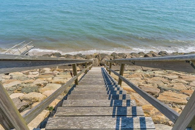 view of dock with a water view and a beach view