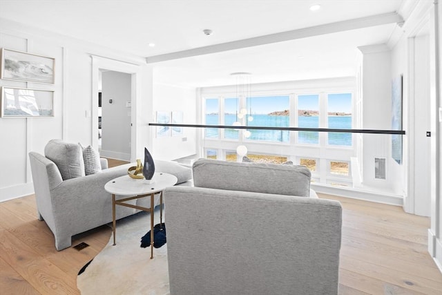 living room featuring light wood finished floors, baseboards, a water view, ornamental molding, and recessed lighting