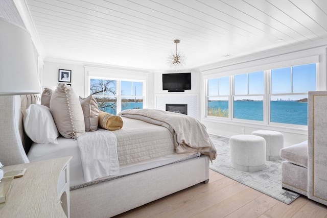 bedroom with a fireplace, wooden ceiling, wood finished floors, and ornamental molding