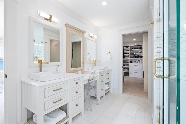 full bath featuring a spacious closet, a shower stall, ornamental molding, two vanities, and a sink