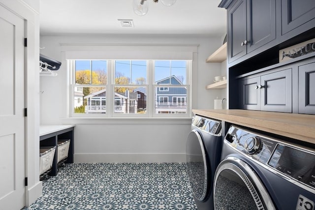 washroom featuring cabinet space, visible vents, washer and dryer, and baseboards