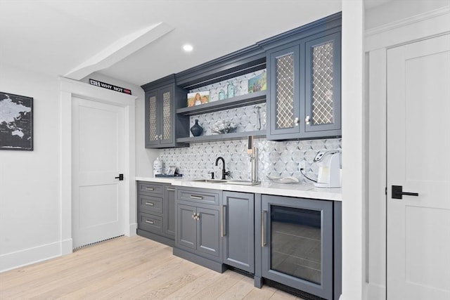 bar with beverage cooler, a sink, backsplash, light wood-style floors, and indoor wet bar