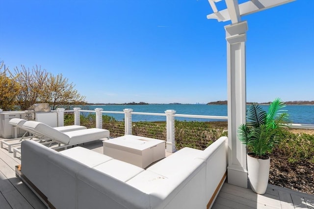 wooden deck featuring an outdoor living space, a water view, and exterior kitchen