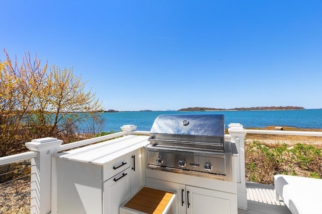 view of patio featuring a water view, area for grilling, and an outdoor kitchen