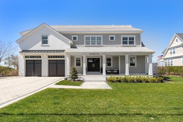 view of front of property featuring a front lawn, a porch, decorative driveway, an attached garage, and a standing seam roof