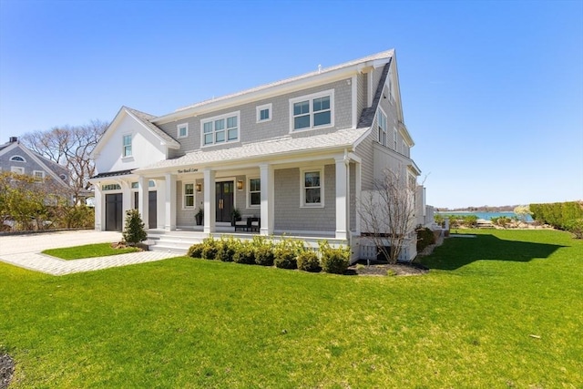 view of front facade with a porch, an attached garage, driveway, and a front lawn