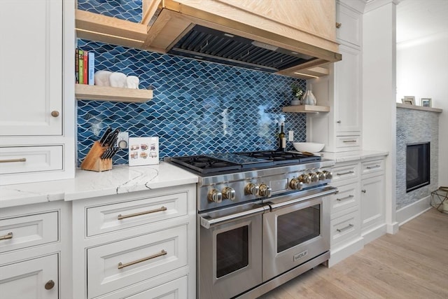 kitchen with light stone counters, white cabinets, double oven range, and open shelves