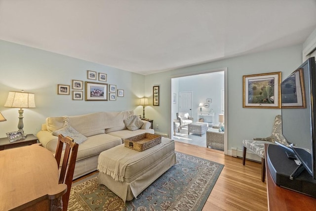 living area featuring a baseboard heating unit, wood finished floors, and baseboards