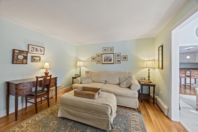 living room featuring a baseboard heating unit, wood finished floors, and baseboards