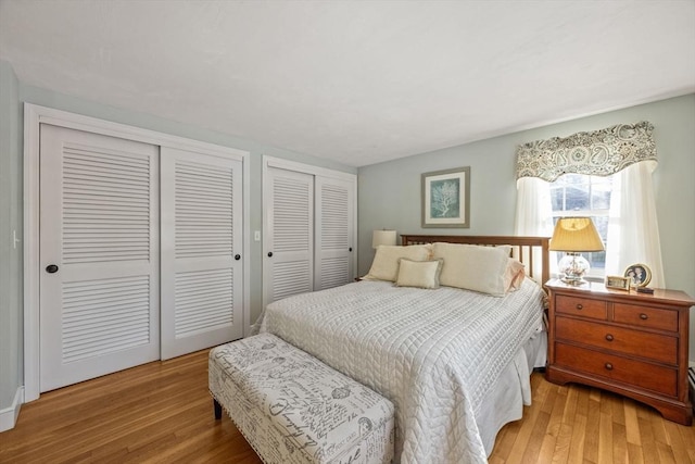 bedroom with light wood-type flooring and multiple closets