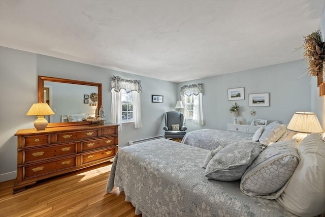 bedroom with a baseboard radiator, baseboards, and wood finished floors