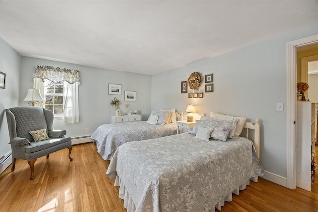 bedroom with baseboards, baseboard heating, and wood finished floors