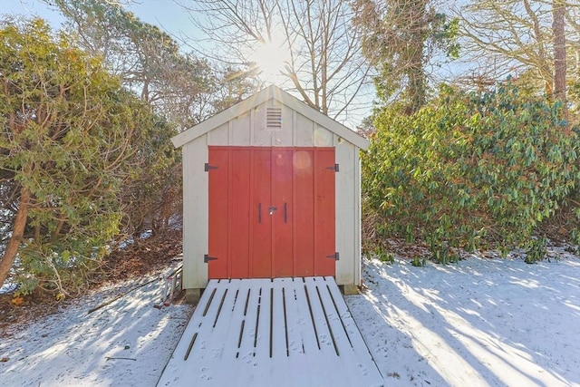 snow covered structure with a storage shed and an outdoor structure