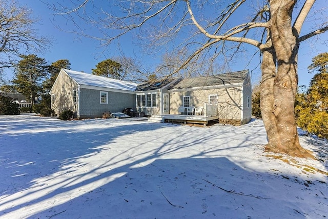 snow covered rear of property featuring a deck