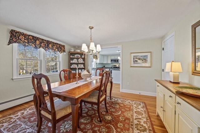 dining room featuring baseboards, a notable chandelier, and light wood-style flooring