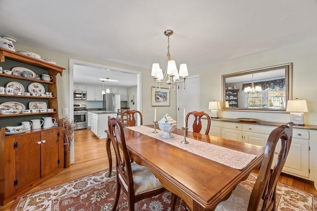 dining space with light wood finished floors and a chandelier