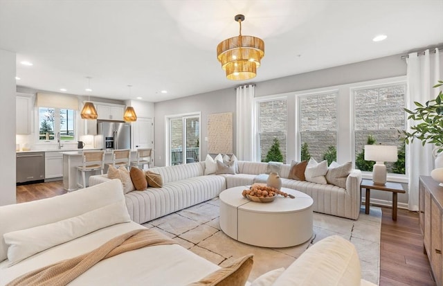 living room with a chandelier, light hardwood / wood-style flooring, and a healthy amount of sunlight