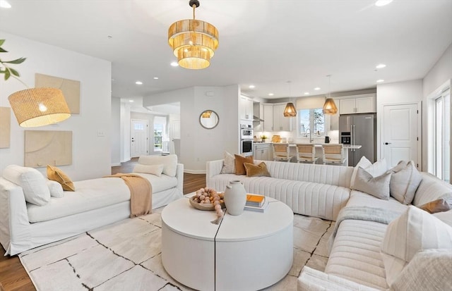 living room with light hardwood / wood-style floors, a wealth of natural light, and a notable chandelier