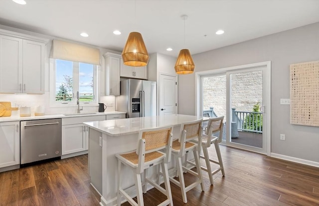 kitchen featuring appliances with stainless steel finishes, decorative light fixtures, white cabinetry, and sink