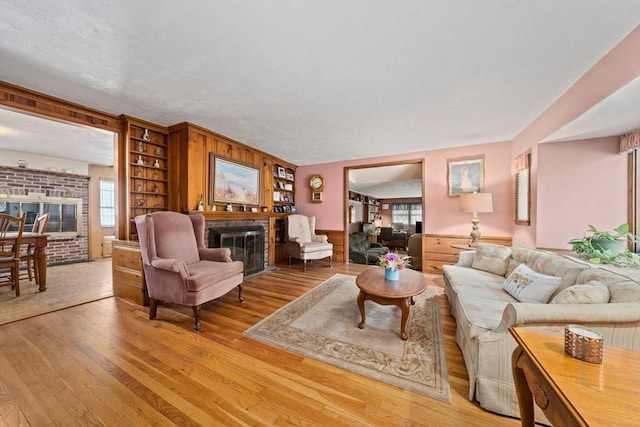 70 Bestick Rd, Braintree, MA 02184 - living area with a brick fireplace, light wood finished floors, wainscoting, and wood walls