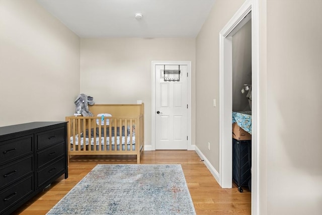 28 Broad St Unit 205, Marlborough, MA 01752 - bedroom with light wood-type flooring, a crib, and baseboards