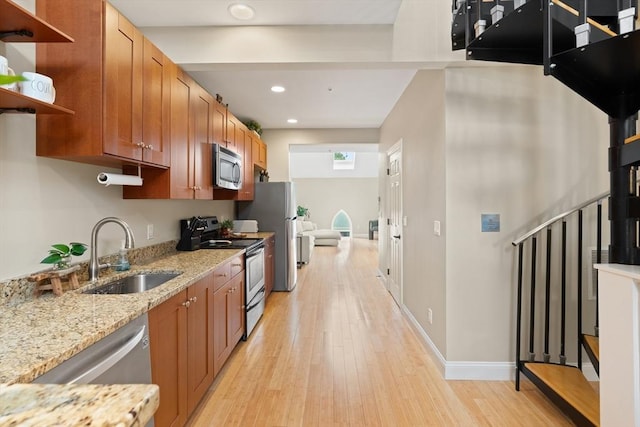 28 Broad St Unit 205, Marlborough, MA 01752 - kitchen featuring stainless steel appliances, a sink, open shelves, light wood finished floors, and brown cabinetry